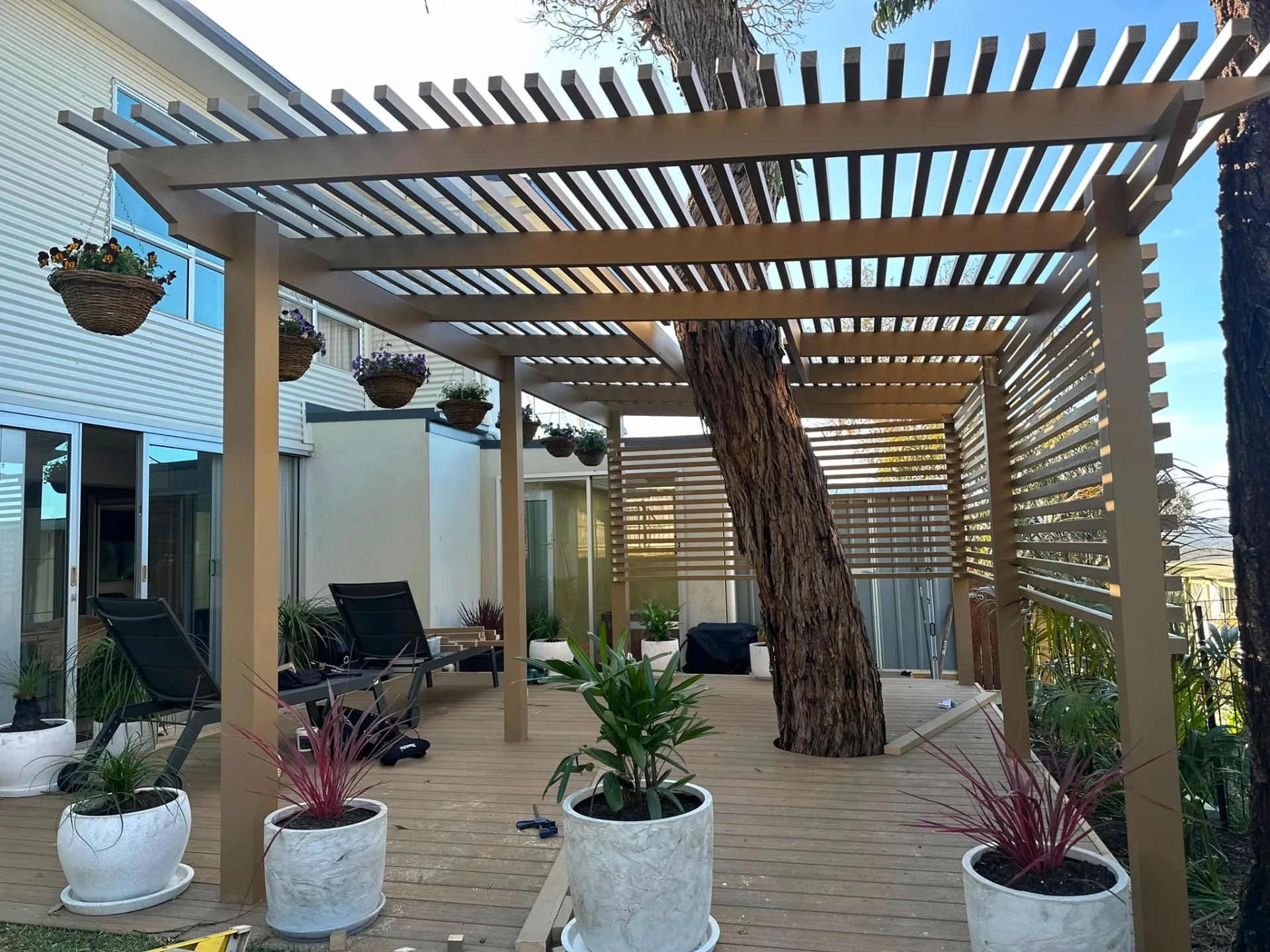 Finished pergola courtyard over a composite deck with hanging baskets and lounge seating