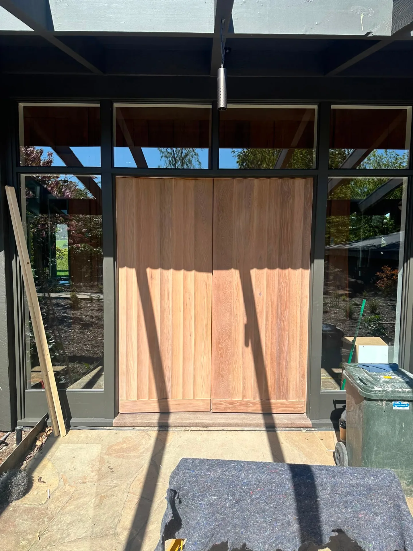 Pair of bespoke fluted timber entry doors hung in a black-framed glazed entry