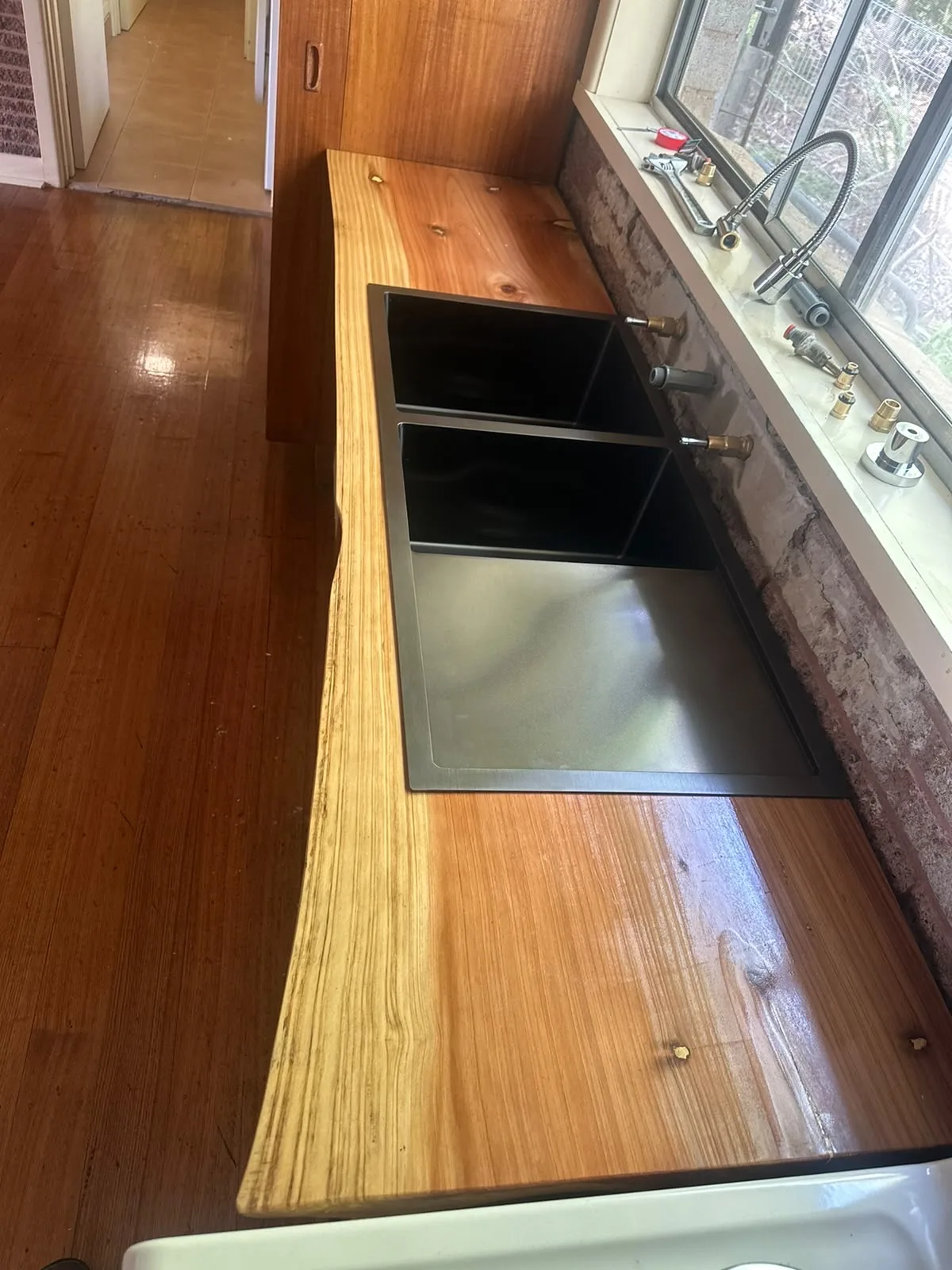 Live-edge timber benchtop with a black undermount double sink, built in by Lovewood Designs