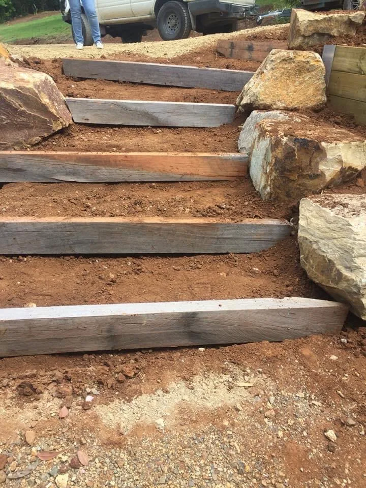 Hardwood sleeper garden steps set into a cut hillside with sandstone boulders