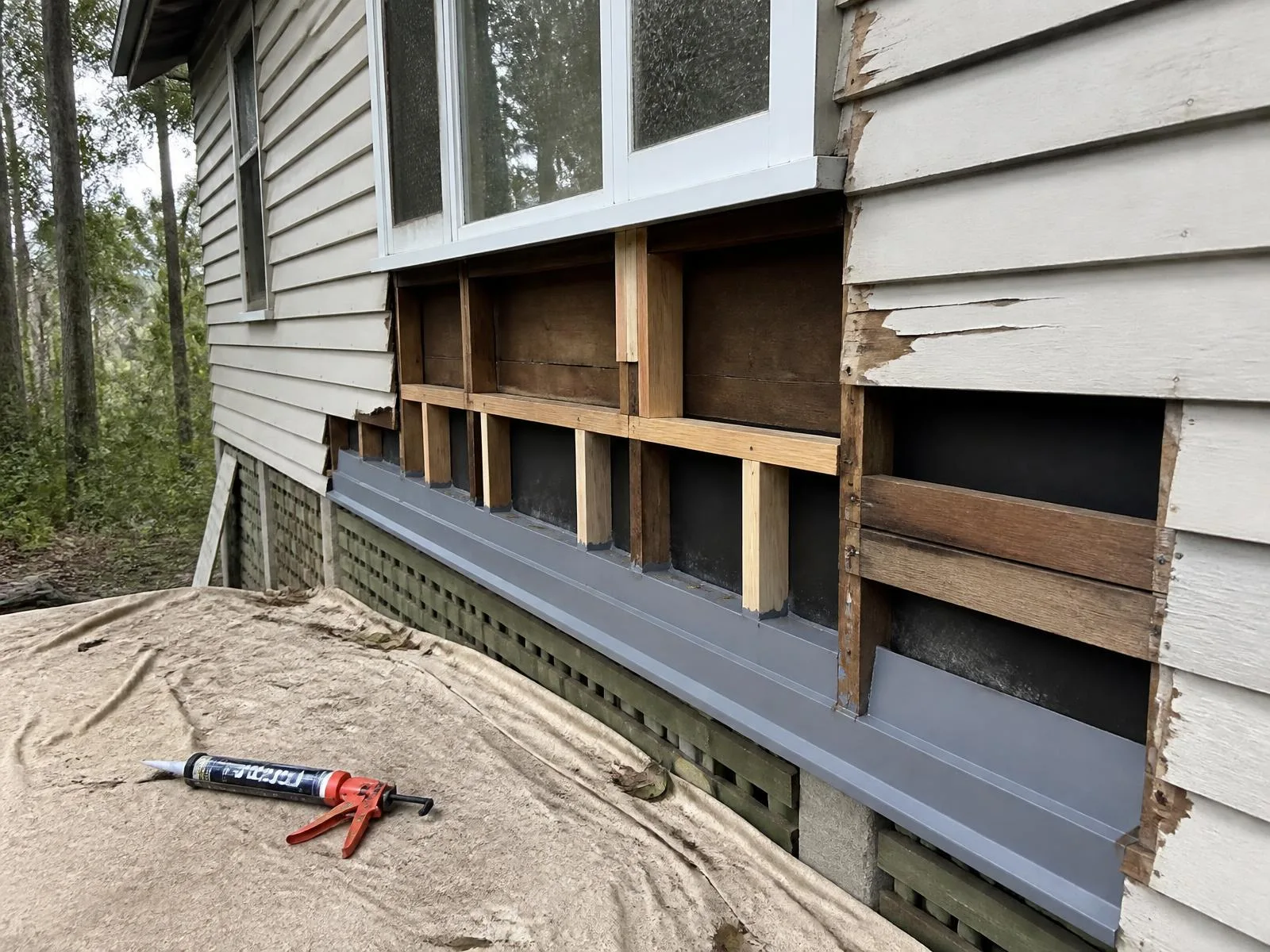 Weatherboard cladding opened up to expose timber framing and new flashing during a water leak repair