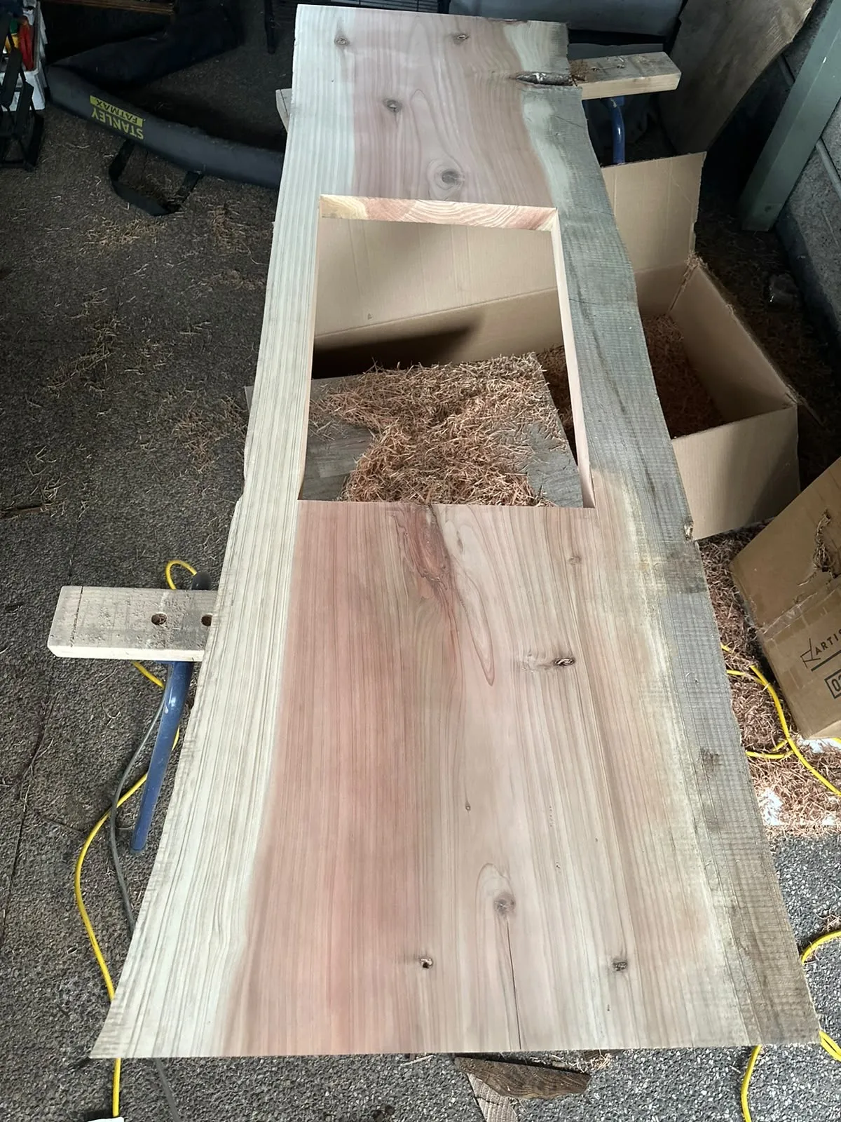 Live-edge timber slab in the workshop with the sink cut-out routed and shavings around it