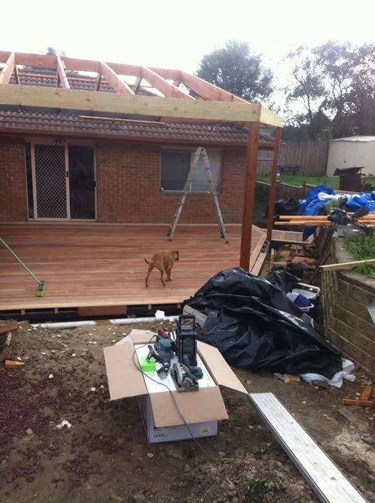 Verandah roof frame going up over a new hardwood deck at the rear of a brick home