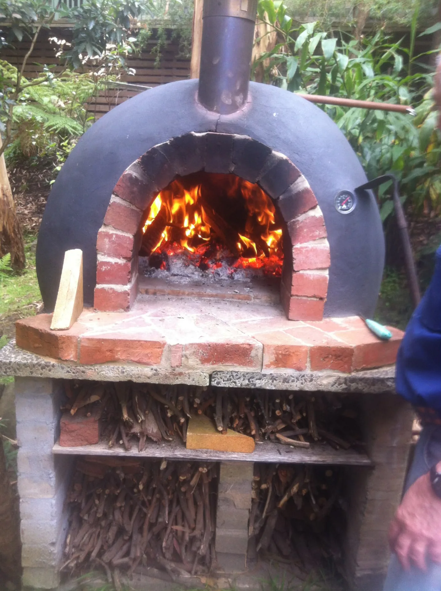 Hand-built brick wood-fired oven alight in a fern-filled Dandenong Ranges garden